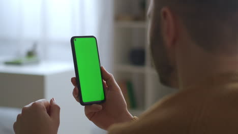 video-chat-in-smartphone-with-green-screen-man-is-listening-and-nodding-head-closeup-view-through-shoulder-technology-for-distant-communication